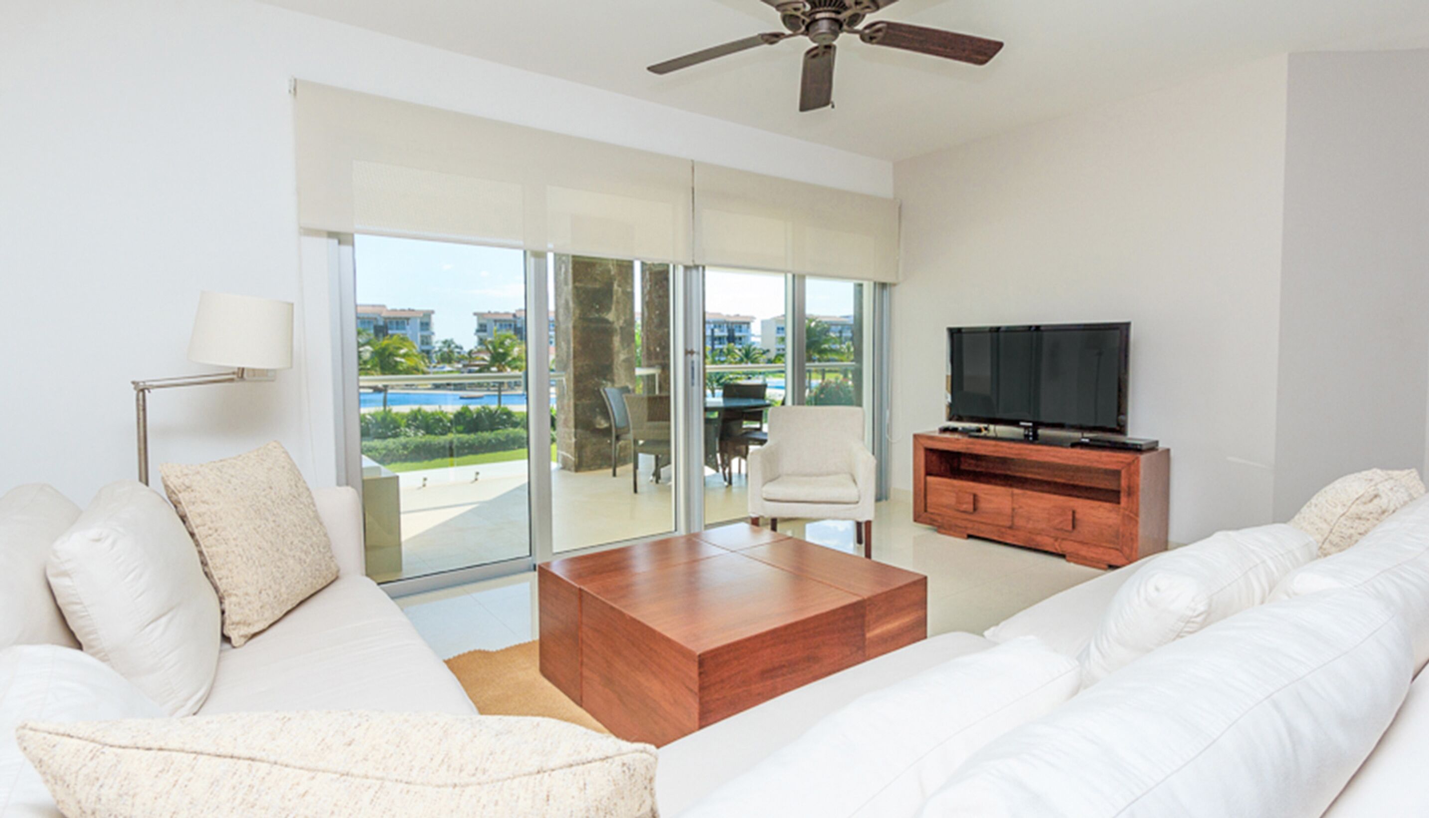 A modern living room with a white sofa, a wooden coffee table, and a television on a wooden stand.