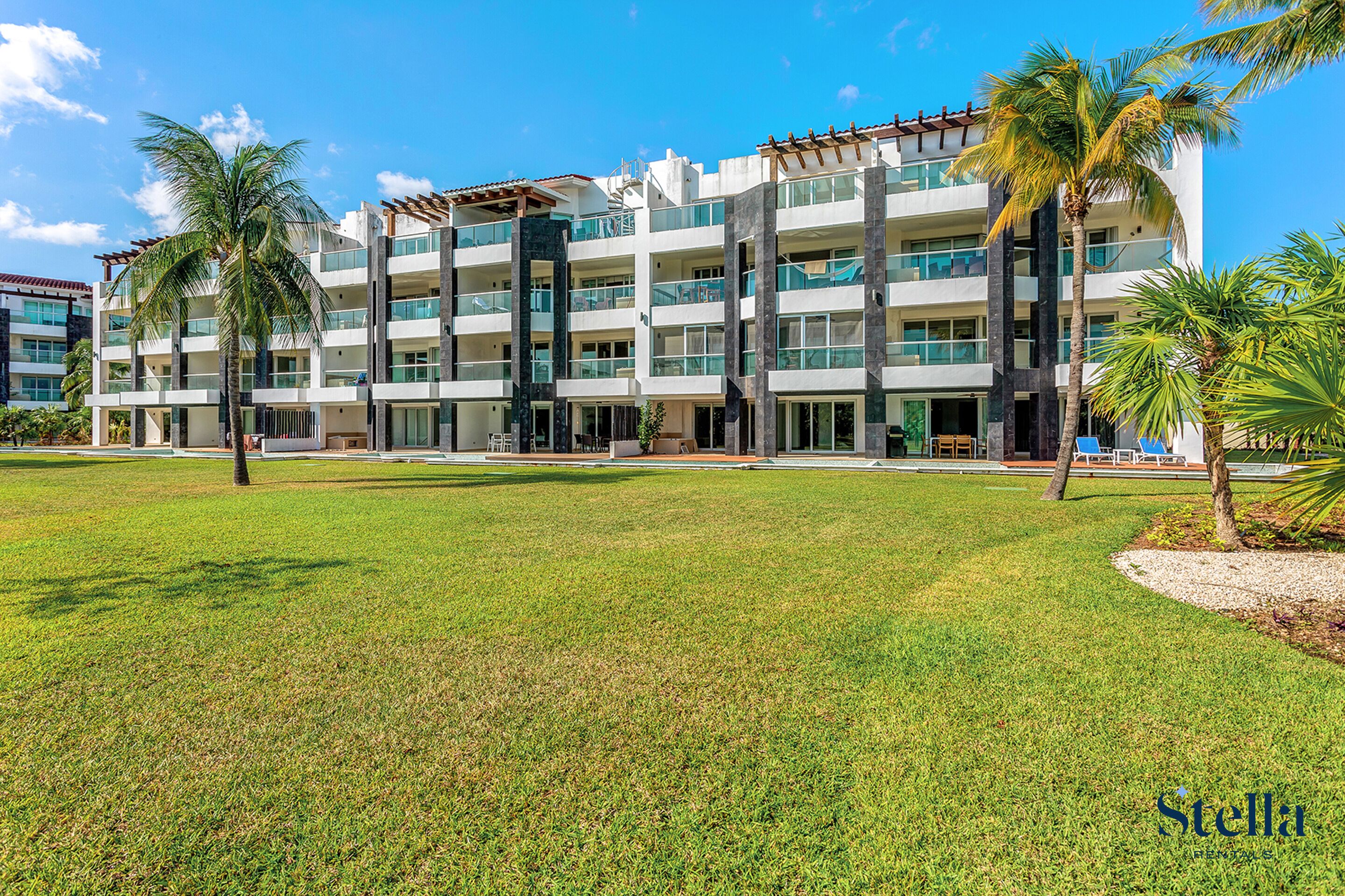 A multi-story hotel with a central courtyard, palm trees, and a clear blue sky.