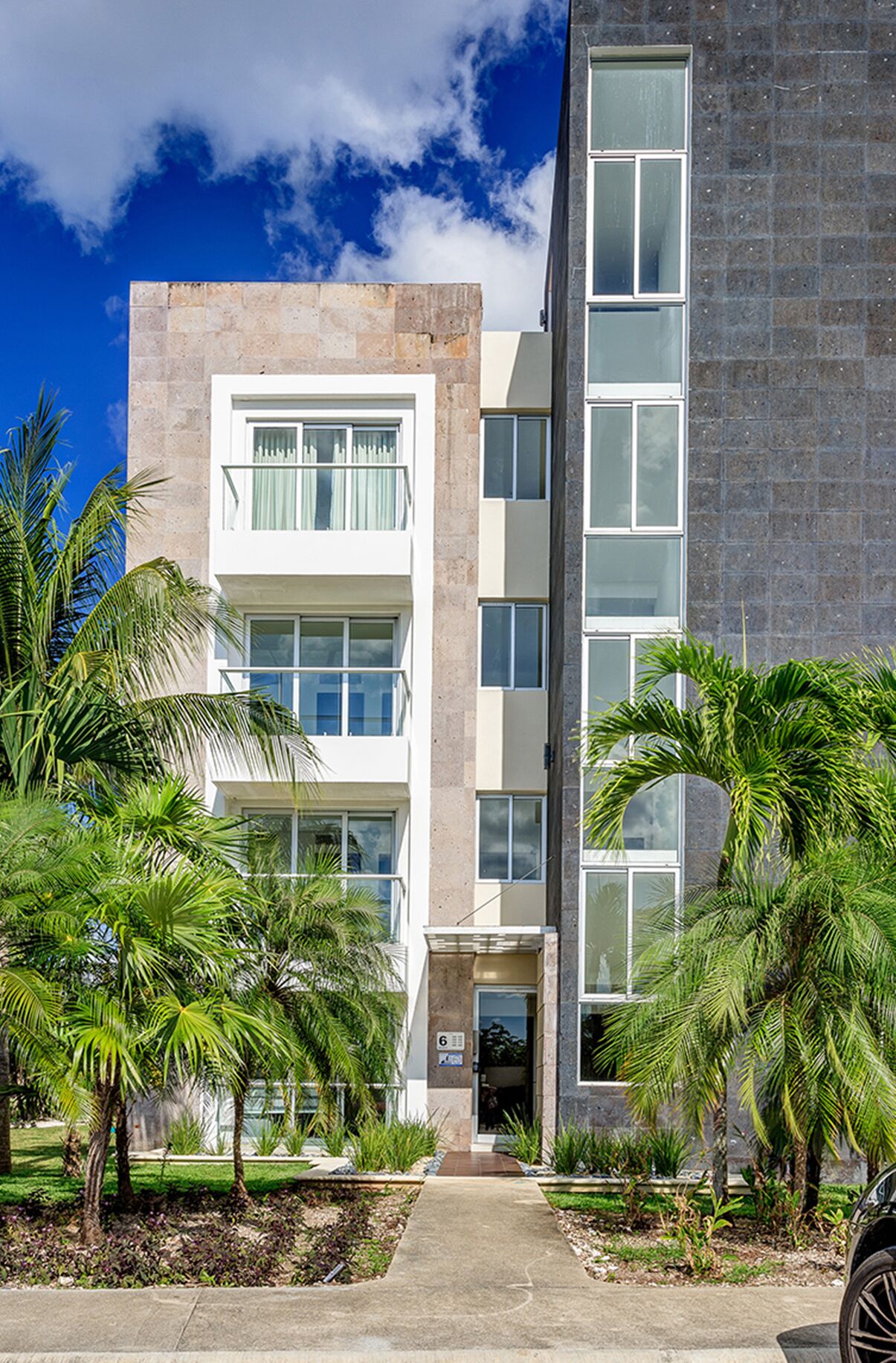 A multi-story building with a modern architectural design, featuring balconies and large windows.