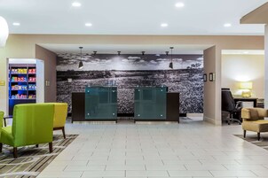 A reception area with a modern design, featuring a large desk, chairs, a snack vending machine, and a mural of a snowy landscape.