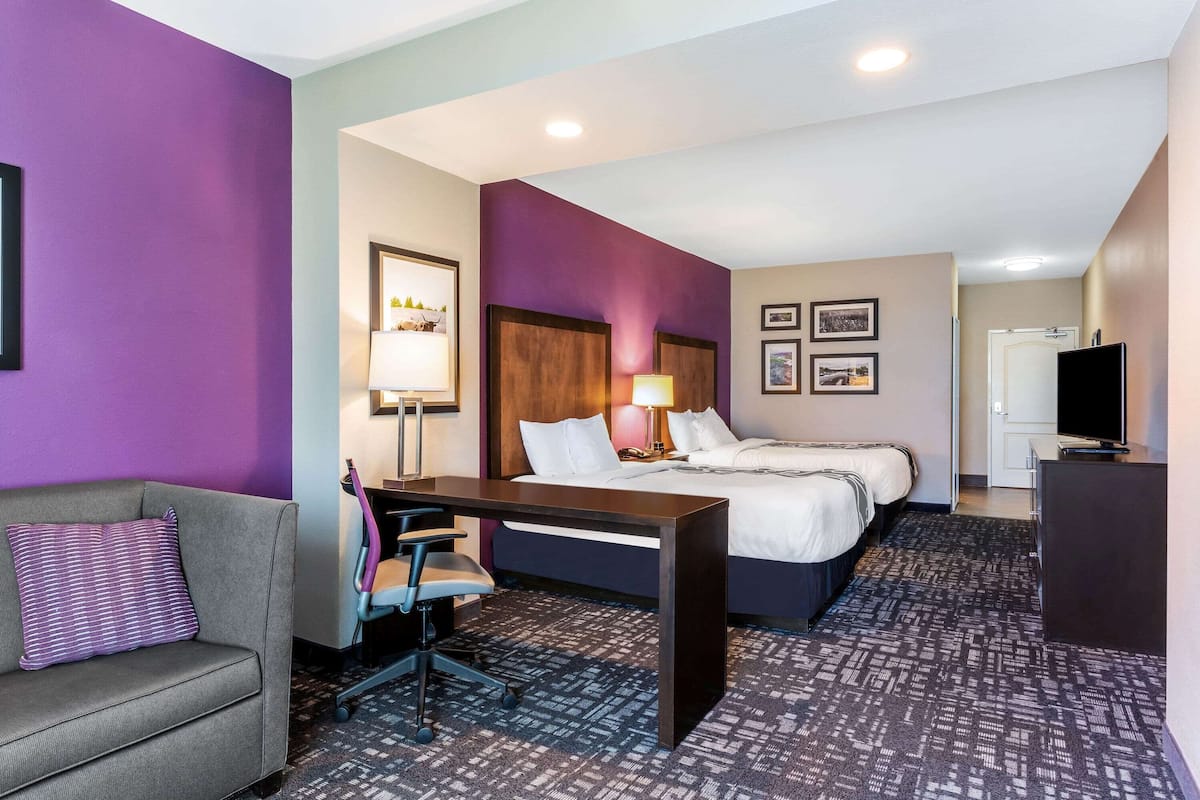A hotel room with a bed, desk, chair, and a television.