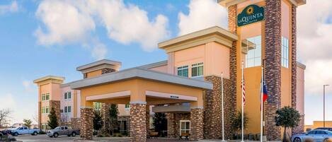 A hotel with a prominent entrance, multiple floors, and a clear sky.