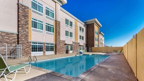 A hotel with a swimming pool, outdoor seating, and a clear blue sky. - La Quinta Inn & Suites by Wyndham Monahans (Monahans)
