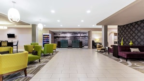 A spacious lobby with modern seating, a reception area, and a large wall mural. - La Quinta Inn & Suites by Wyndham Monahans (Monahans)