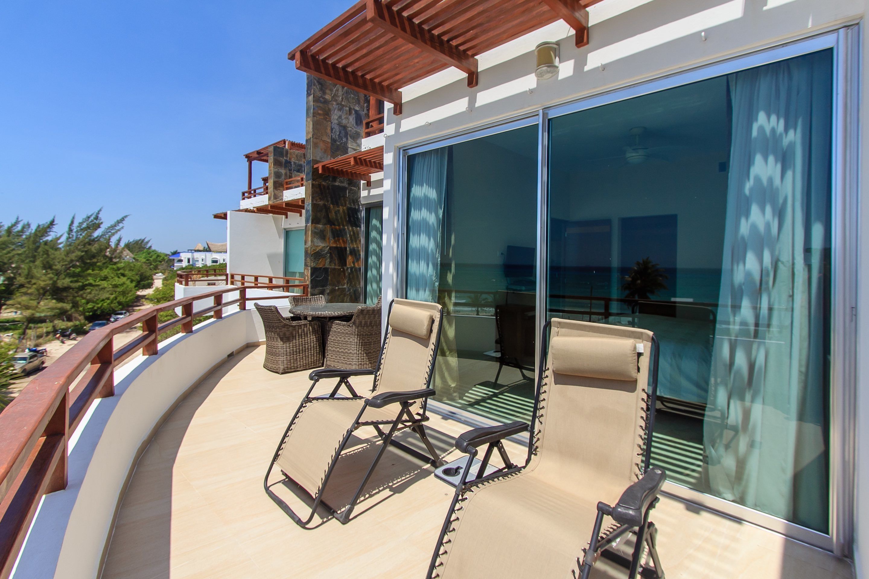 A balcony with two lounge chairs and a table, overlooking a scenic view.