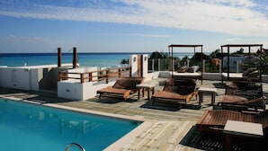 Area piscina con lettini e un pontile di legno con vista sull'oceano.