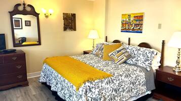Un dormitorio con una cama, un aparador, un espejo y dos cuadros en la pared.