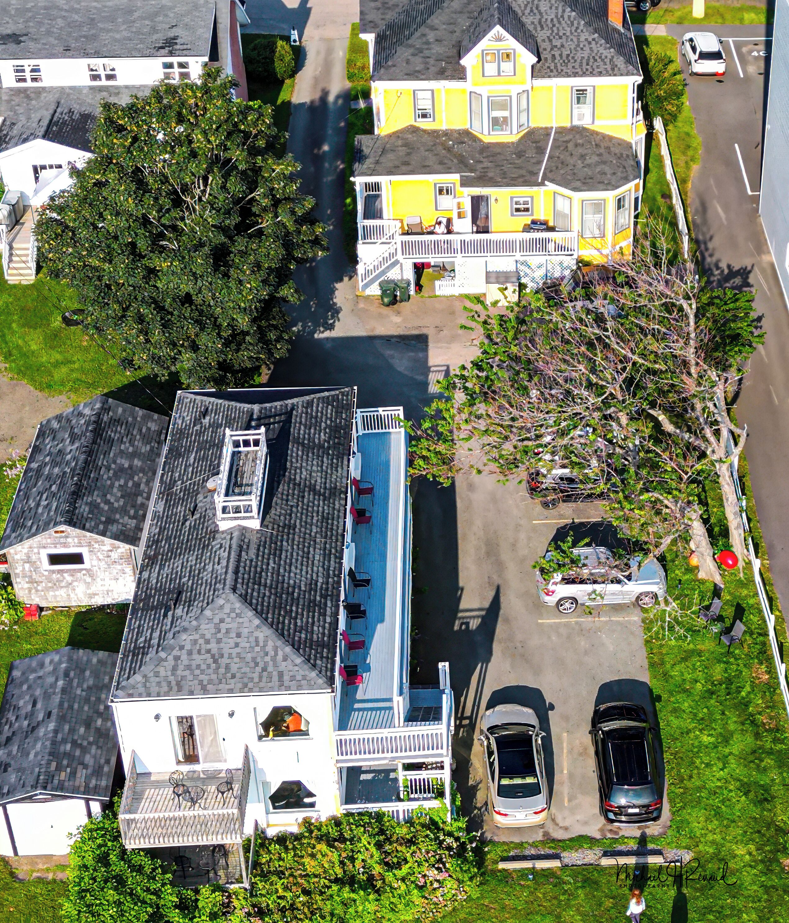 An aerial view of a residential area with houses, a swimming pool, and parked cars.