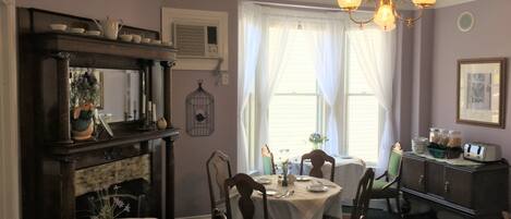 A dining room with a fireplace, a chandelier, and a dining table set for four.