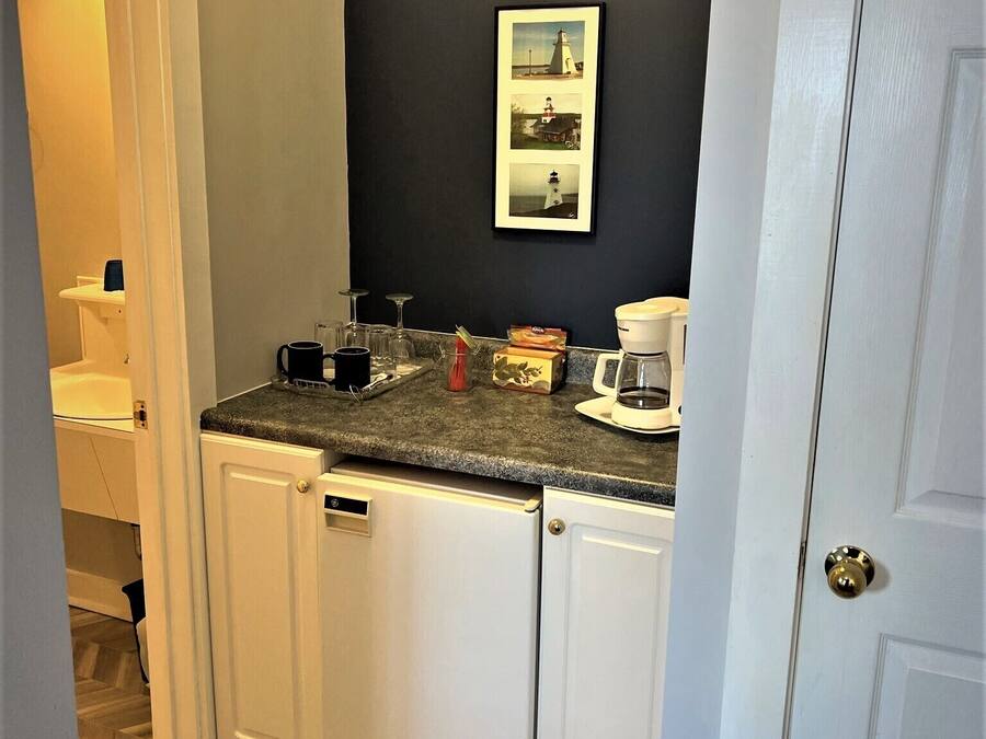 A compact kitchen with white cabinets, a granite countertop, and a dark wall.