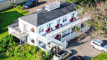 A multi-story building with balconies, a covered front porch, and a parking area.