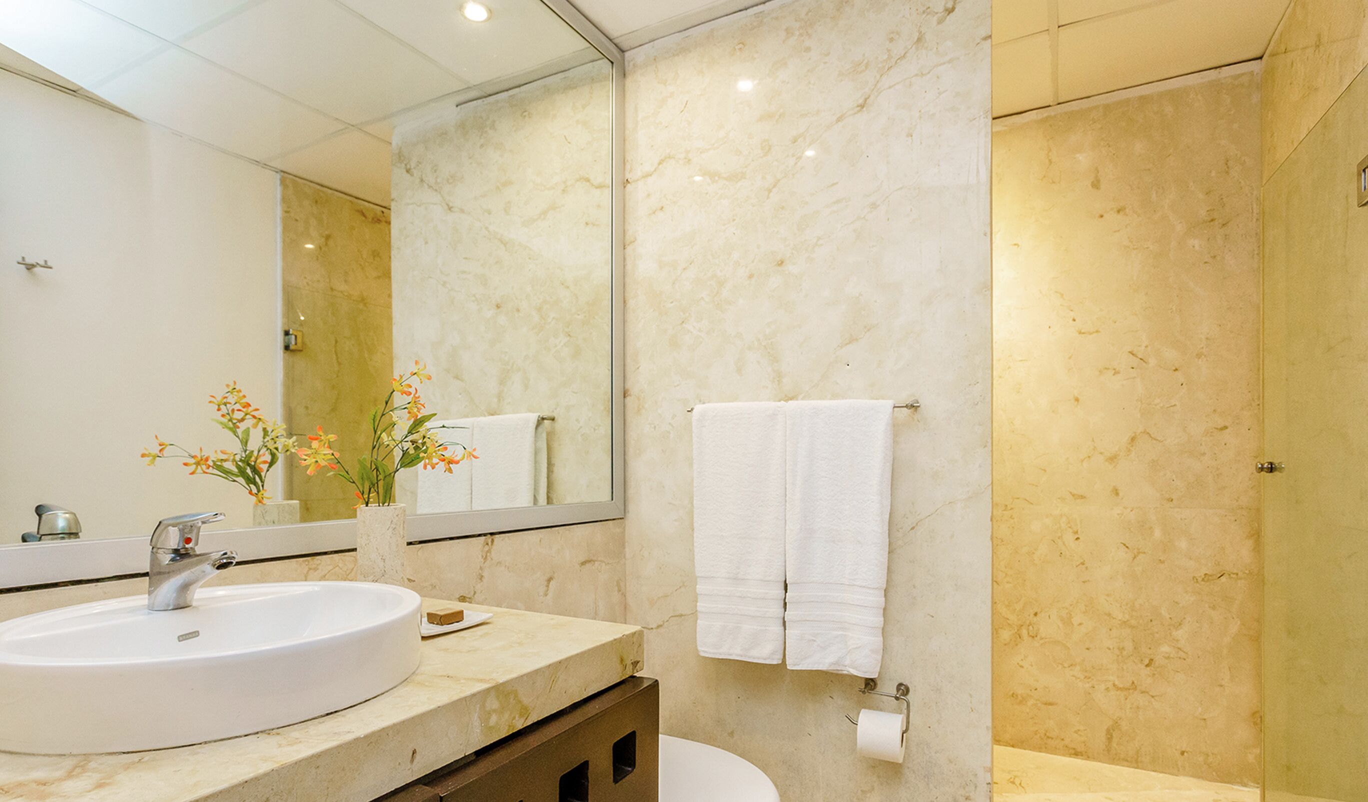 Ein Badezimmer mit großem Spiegel, Waschbecken, Toilette und Duschbereich.