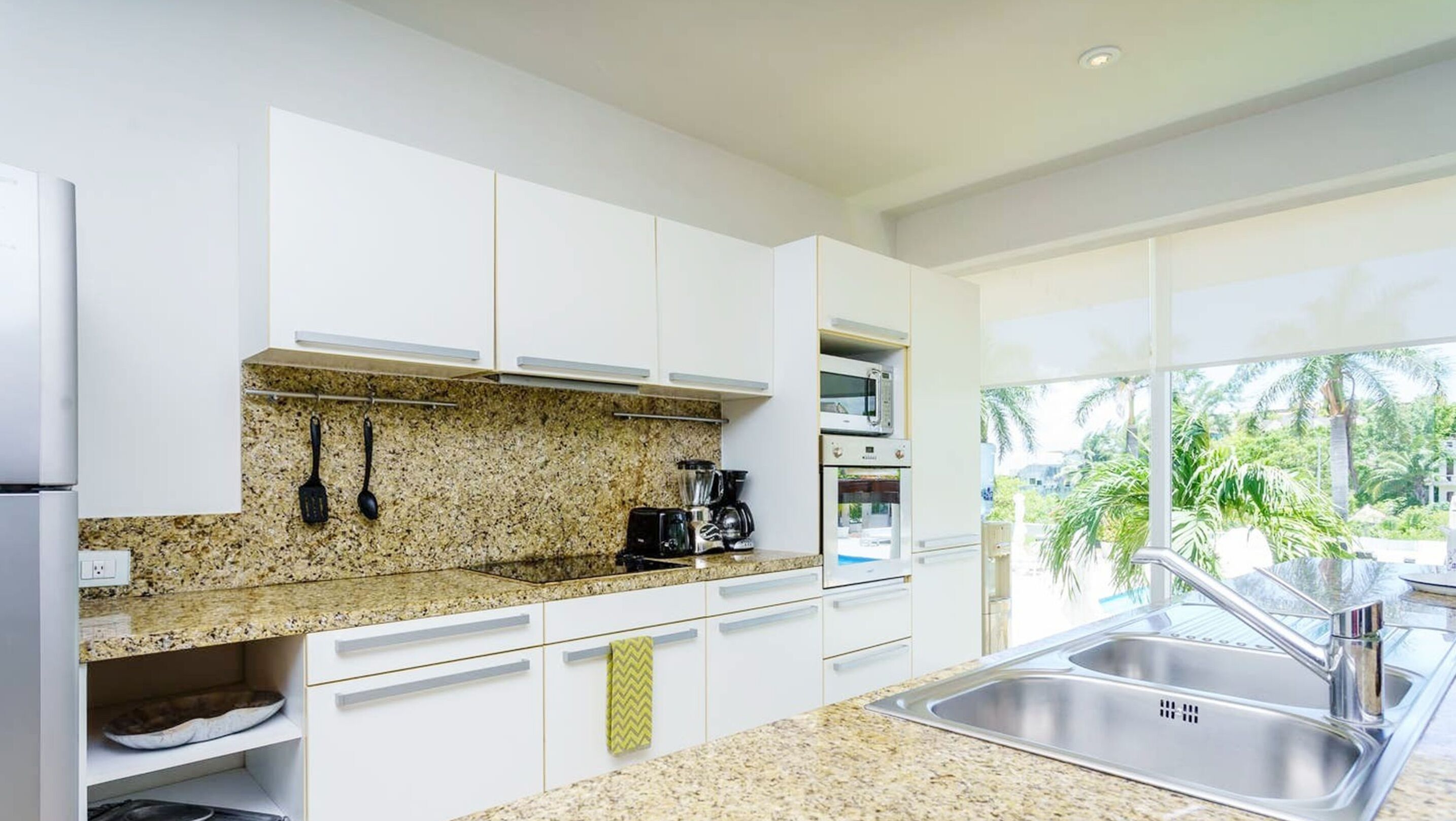 Una cocina moderna con armarios blancos, encimeras de granito y electrodomésticos de acero inoxidable.