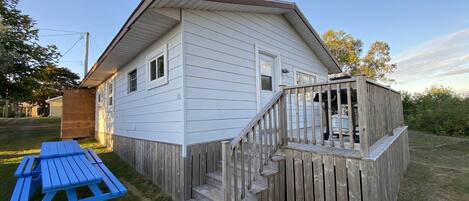 A single-story house with a wooden deck and a picnic table.