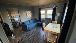 Une pièce chaleureuse avec un canapé bleu, une table à manger en bois et un petit coin cuisine.