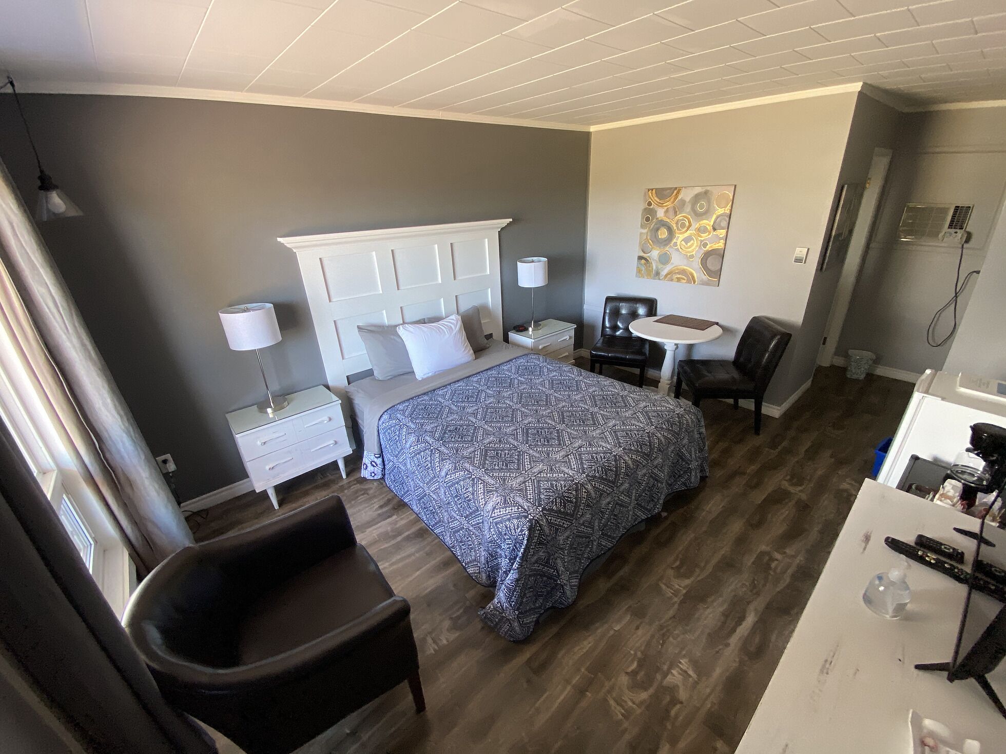 A hotel room with a bed, a desk, a chair, and a small table.