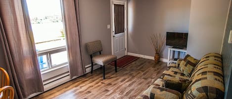 A living room with a sofa, a chair, a television, and a door.