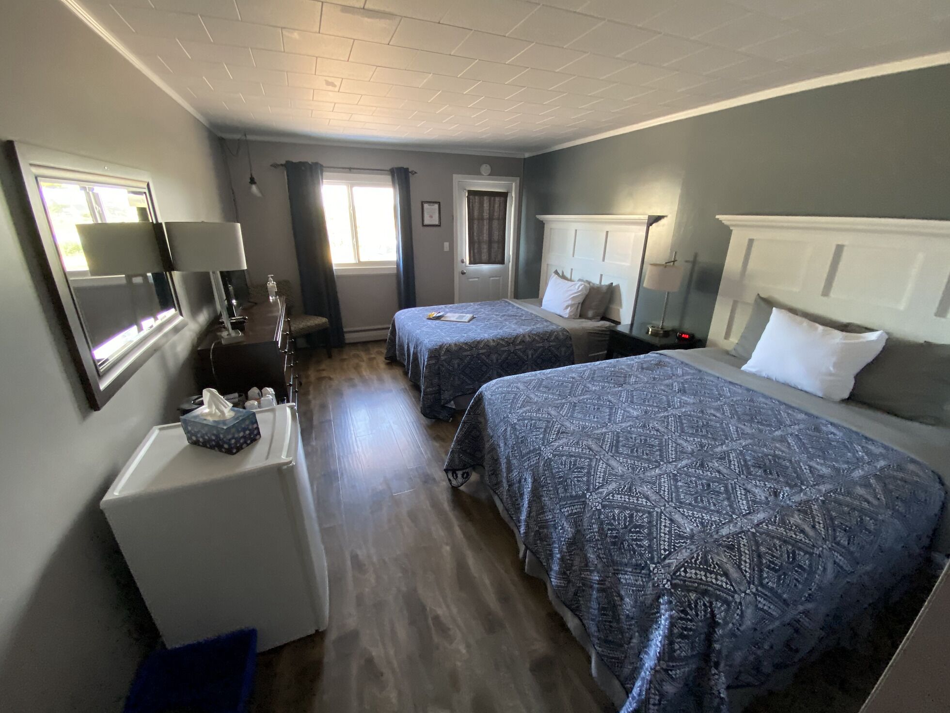 A hotel room with two beds, a desk, a chair, a TV, and a window with curtains.