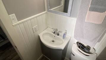 A bathroom with a white sink, mirror, and toilet.