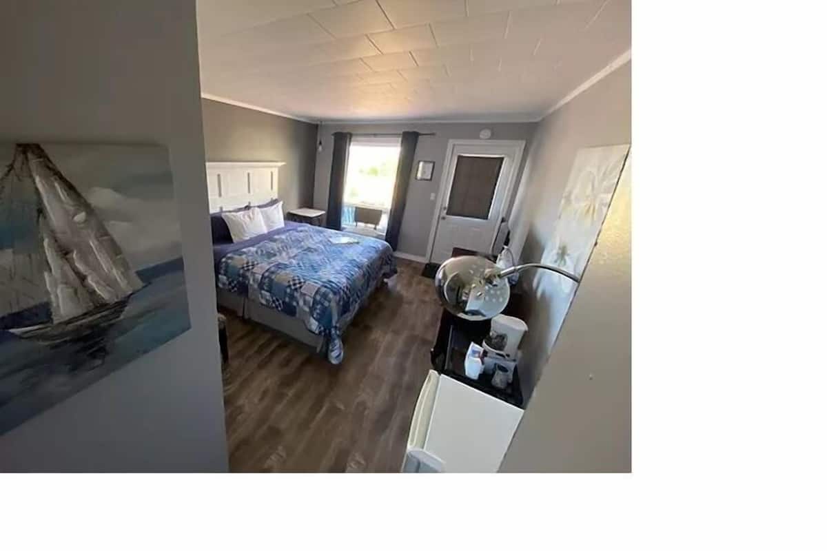 Un dormitorio con cama, mesita de noche, espejo y puerta.