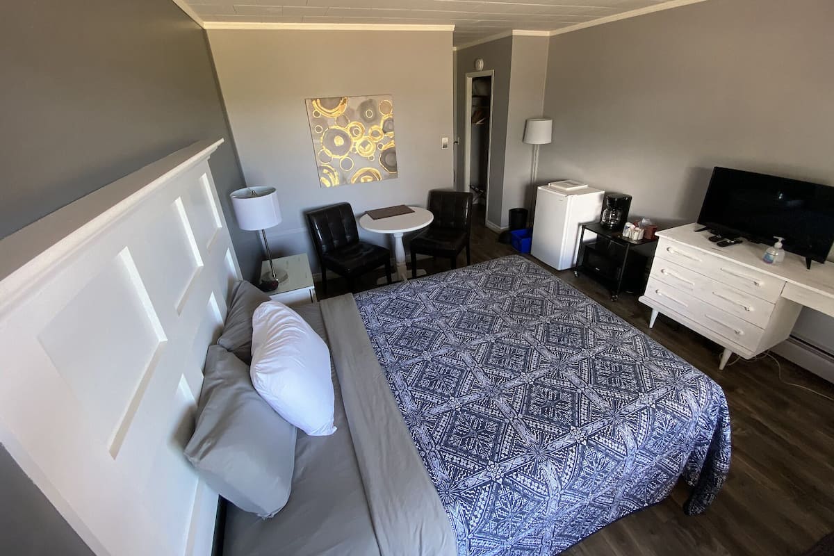 Una habitación de hotel con cama, escritorio, silla, televisor y una pequeña mesa.