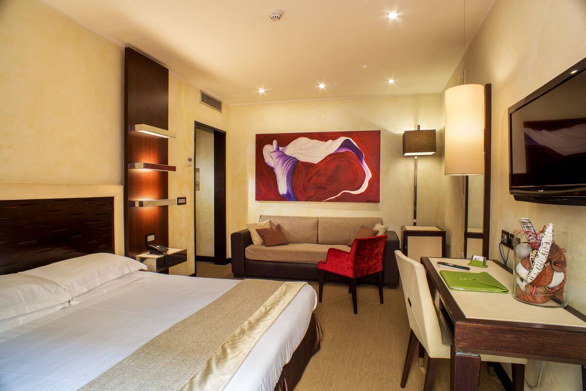 Een hotelkamer met een groot bed, een bank, een bureau en een televisie.