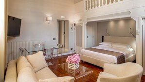 Een moderne hotelkamer met een glazen eettafel, een bank, een bed en een balkon.