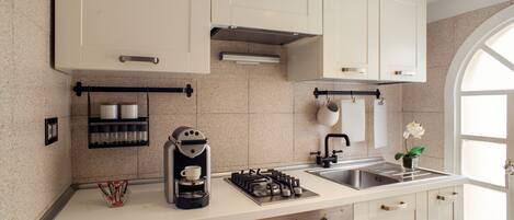 A modern kitchen with a gas stove, coffee maker, and a sink.