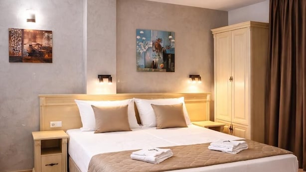 Ein Hotelzimmer mit einem großen Bett, Nachttischen, einem Kleiderschrank und Bildern an den Wänden.