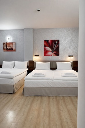 Een hotelkamer met twee bedden, een licht houten vloer, een groot bloemwerk aan de muur en een rookmelder in het plafond.
