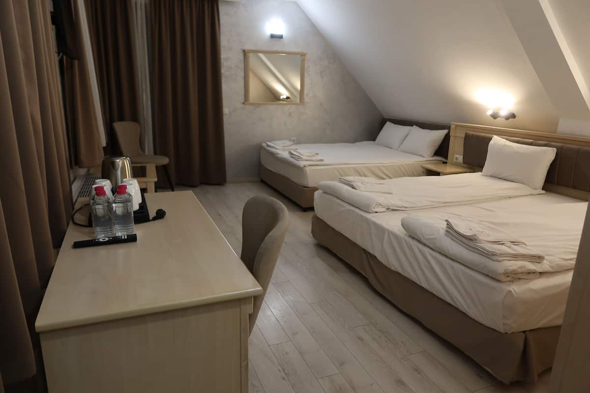 A hotel room with two beds, a desk, a chair, a mirror, and a nightstand.