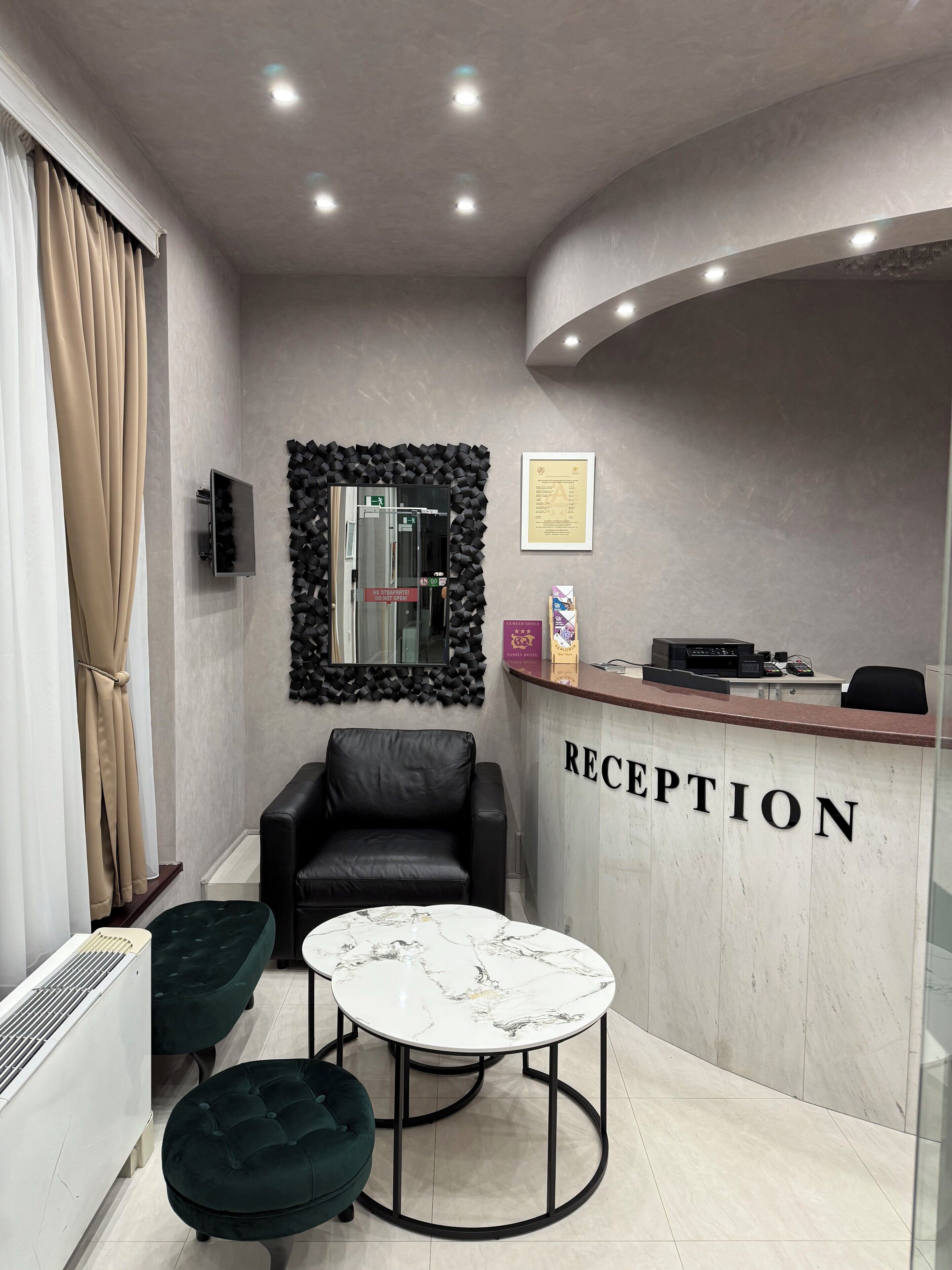 Un área de recepción con una mesa de mármol, sillas de cuero, un mostrador de recepción y un televisor montado en la pared.