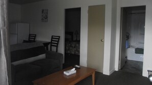 Una habitación de hotel compacta con una cama individual, un pequeño sofá, una mesa de madera y una televisión.