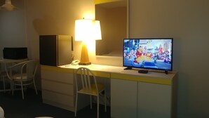 Una habitación de hotel con cama, escritorio con lámpara, televisión y una silla.
