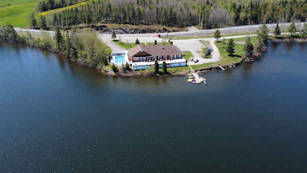 A lakeside property with a large house, a swimming pool, and docked boats. - Auberge du Lac Malcom (Sayabec)