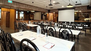 A conference room with tables, chairs, a projector screen, and a wooden panel wall. - Northern Motor Inn (Terrace)