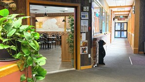 A hotel lobby with a reception desk, a dining area with chairs and tables, and a corridor leading to a bar area. - Northern Motor Inn (Terrace)