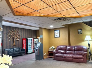 A lobby with a sofa, a Coca-Cola refrigerator, an ATM, a wall-mounted clock, and a lamp. - Northern Motor Inn (Terrace)