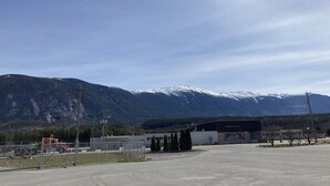 A parking lot with a building in the foreground and snow-capped mountains in the background.