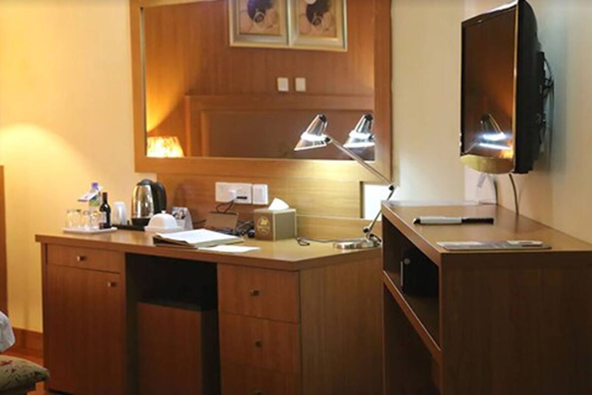 Una habitación de hotel con un escritorio de madera, un espejo, una lámpara, un televisor y una cama.