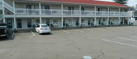 Ein Motel mit rotem Dach, weißer Fassade und einem Parkplatz mit mehreren Autos.
