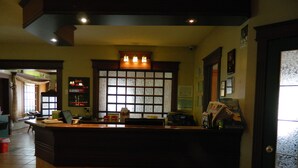A reception desk with a window, a bulletin board, and a counter with various items. - Hill Top Motel & Restaurant (Grand Falls)