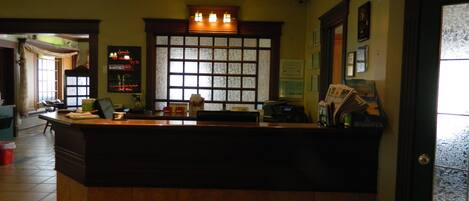 A reception desk with a window, a bulletin board, and a counter with various items.