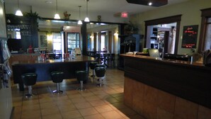 A bar area with a counter, stools, and a sign indicating specials. - Hill Top Motel & Restaurant (Grand Falls)