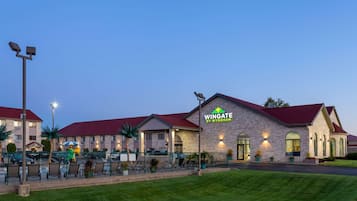 Guests can enjoy a well-maintained lawn and outdoor seating areas with chairs and umbrellas.