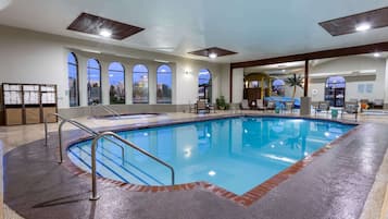 An indoor swimming pool with clear glass walls, a tiled floor, and a wooden ceiling.