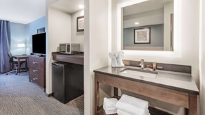 A hotel room with a desk, chair, minibar, and a large mirror above the sink. - Wingate by Wyndham Wisconsin Dells Waterpark (Baraboo)