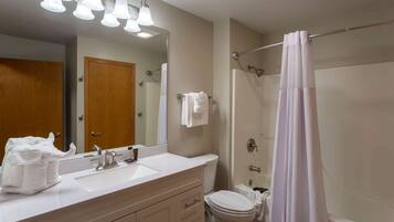 A bathroom with a sink, mirror, towel rack, toilet, and shower curtain.
