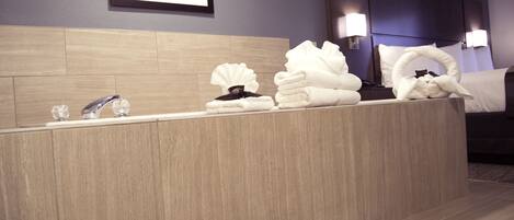Un baño de hotel con tocador de madera, lavamanos y cama con cabecera.