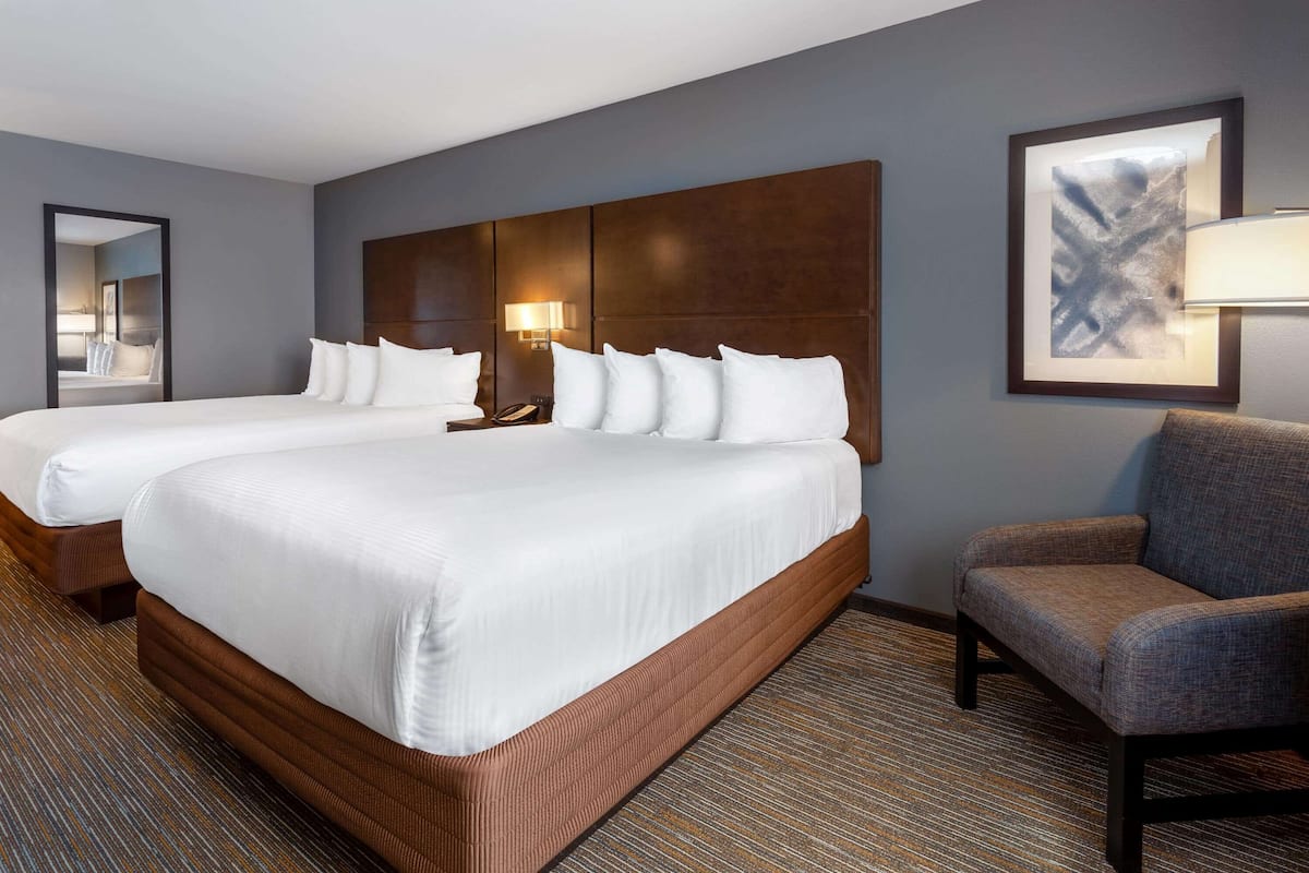 A hotel room with two beds, a seating area, and a large mirror.